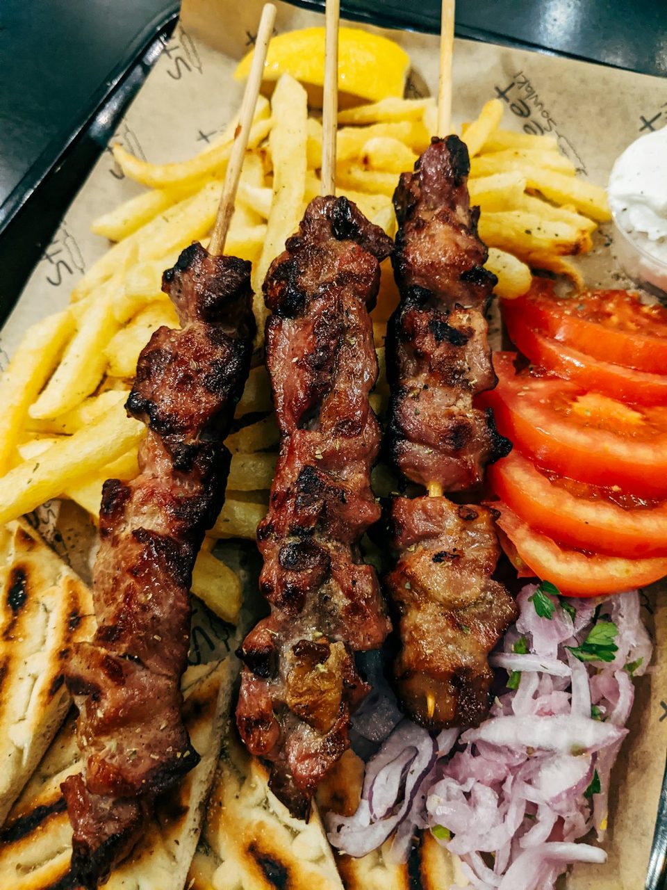 Souvlaki-Spieße mit Pita, Pommes, Tomaten und roten Zwiebeln